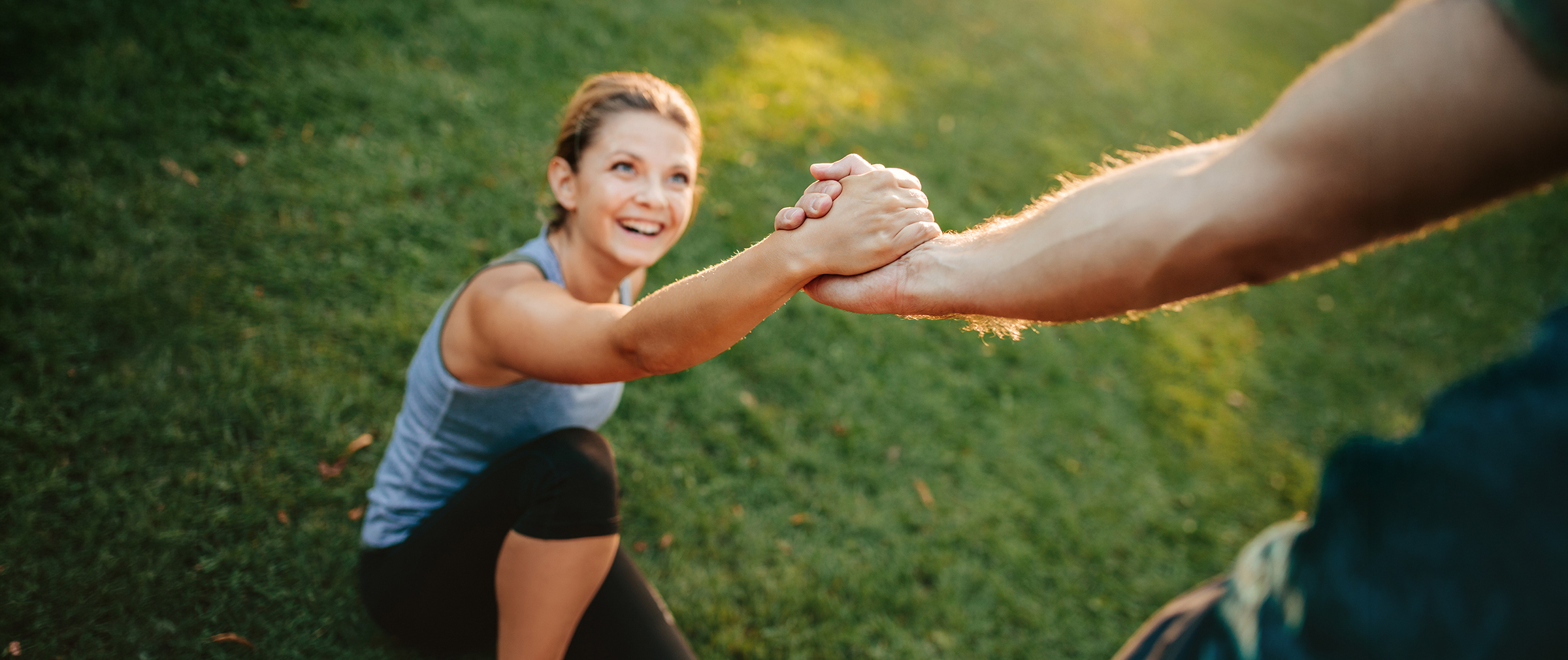 Man helping her girlfriend with focus on hands. Couple exercising in park.